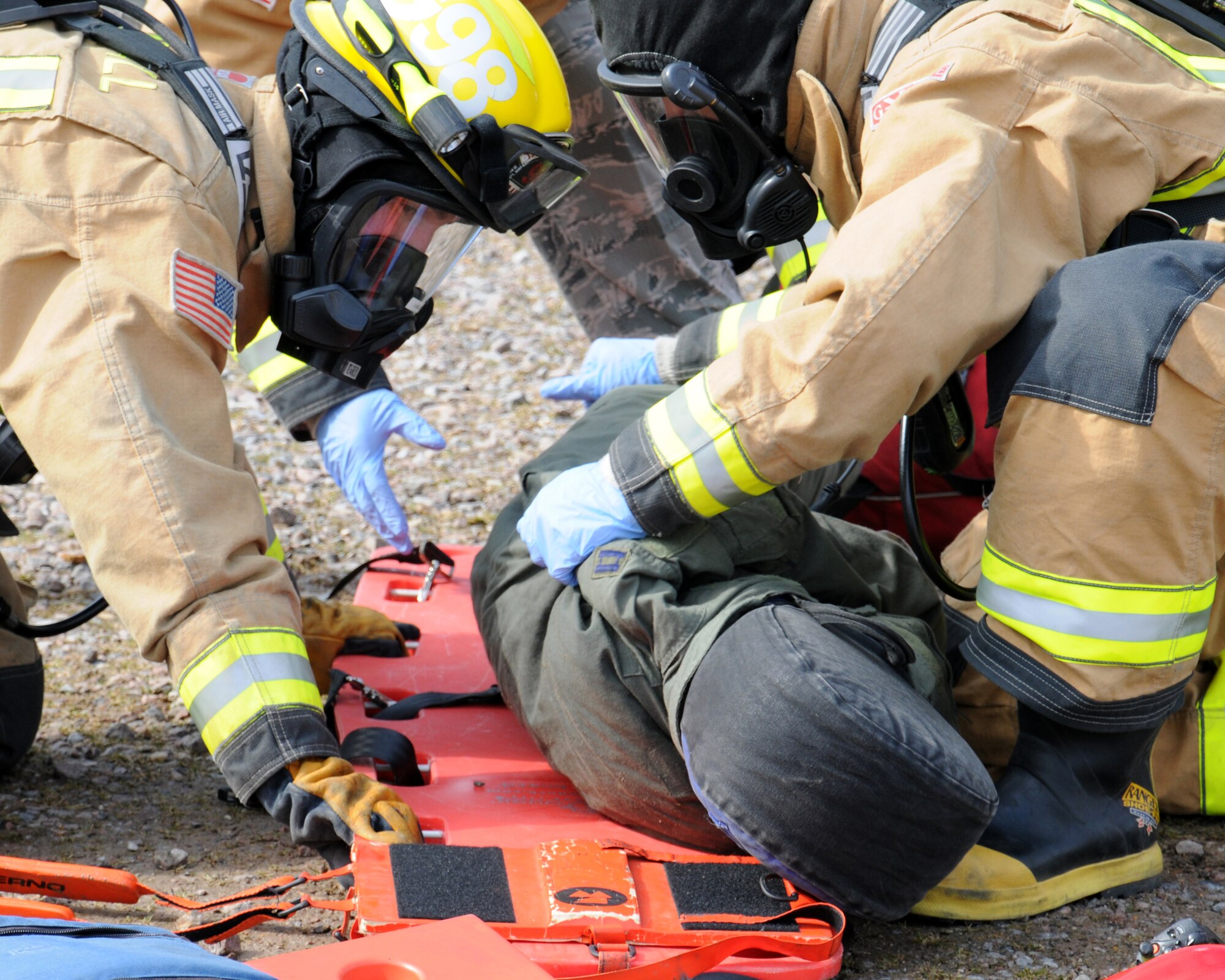 100th Civil Engineer Squadron Fire Department firefighters prepare to move a simulated patient to an ambulance for medical care during an exercise March 25, 2013, at RAF Mildenhall, England. The scenario involved lightning striking a building, which caused a fire. A person ran out of the building and got hit by a car, which then hit another car, turning it upside down and trapping three people. Firefighters prioritized their response, as the vehicle accident was a risk to life, while the building wasn't considered mission-essential. The first responders rescued the simulated victims from the vehicle and transported them to safety until medics appeared on-scene. (U.S. Air Force photo by Gina Randall/Released)