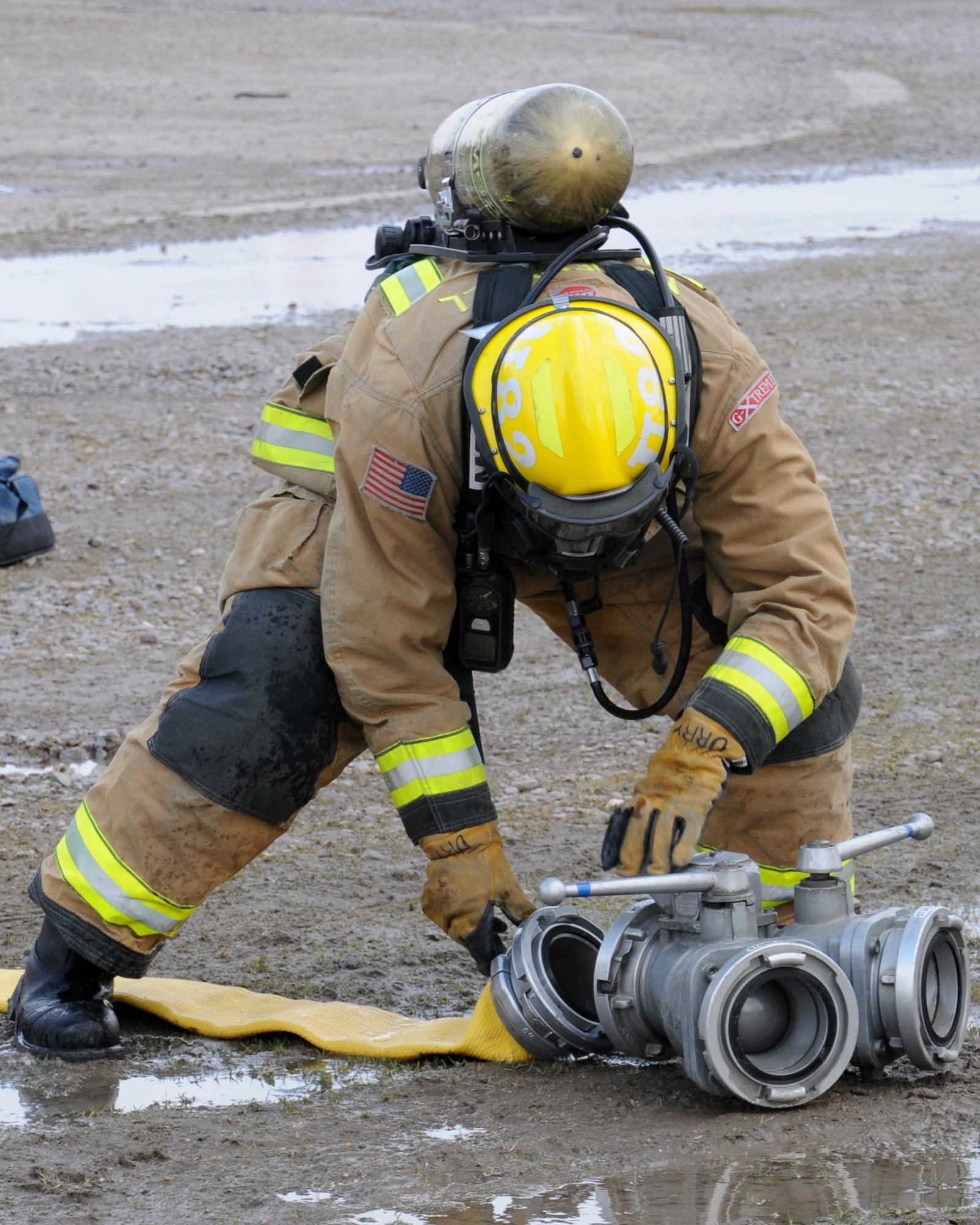 A firefighter with the 100th Civil Engineer Squadron Fire Department prepares a fire hose during an exercise March 25, 2013, at RAF Mildenhall, England. The scenario involved lightning striking a building, which caused a fire. A person ran out of the building and got hit by a car, which then hit another car, turning it upside down and trapping three people. Firefighters prioritized their response, as the vehicle accident was a risk to life, while the building wasn't considered mission-essential. The first responders rescued the simulated victims from the vehicle and transported them to safety until medics appeared on-scene. (U.S. Air Force photo by Gina Randall/Released)