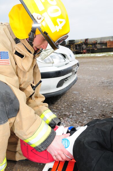 Senior Airman Zachary Peterson, 100th Civil Engineer Squadron Fire Department firefighter from Salt Lake City, Utah, holds a C-spine manual stabilization collar on a simulated patient in triage while the patient is immobilized on a backboard during an operational readiness exercise March 25, 2013, at the fire training area on RAF Mildenhall, England.  Firefighters responded when simulated lightning struck a facility and started a fire. The scenario simulated a person who ran out of the building and got hit by a car, which then hit another car, causing it to overturn with three simulated casualties inside. (U.S. Air Force photo by Karen Abeyasekere/Released)