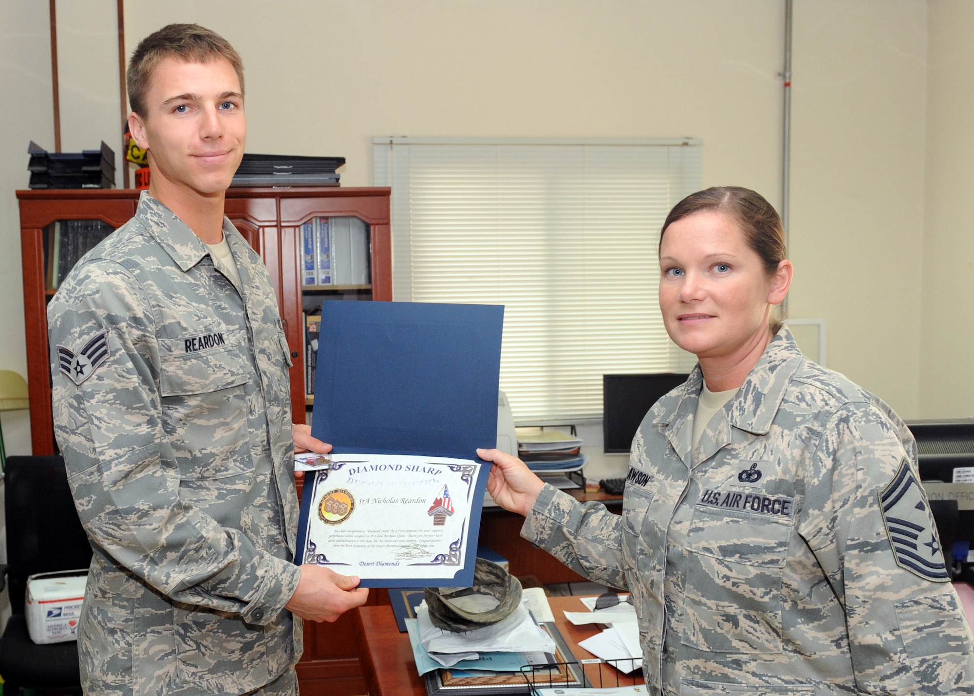 SOUTHWEST ASIA - Senior Master Sgt. Sheila Lawson, 379th Expeditionary Maintenance Squadron first sergeant, presents Senior Airman Nicholas Reardon, 379th Expeditionary Communications Squadron, with the Diamond Sharp Award March 26. The First Sergeants of the Desert Diamond Council recently created the award to recognize Airmen for stellar performance. (U.S. Air Force photo/Senior Airman Joel Mease)