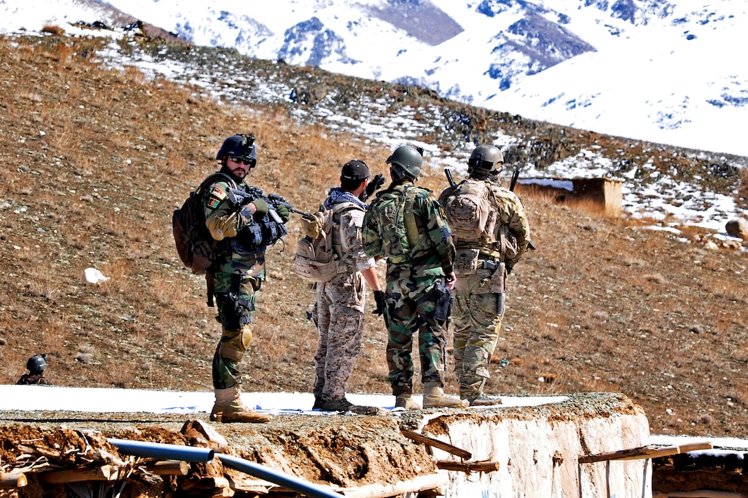 U.S. Special Forces and Afghan commandos provide security from a rooftop while residents of the Siya Boghal village walk to a shura, or meeting, in the northern Khas Uruzgan district of Afghanistan's Uruzgan province, March 16, 2013.