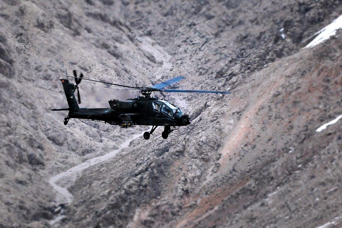 An AH-46 Apache helicopter flies over the mountains providing security while escorting other helicopters in Afghanistan's Uruzgan province, March 16, 2013.