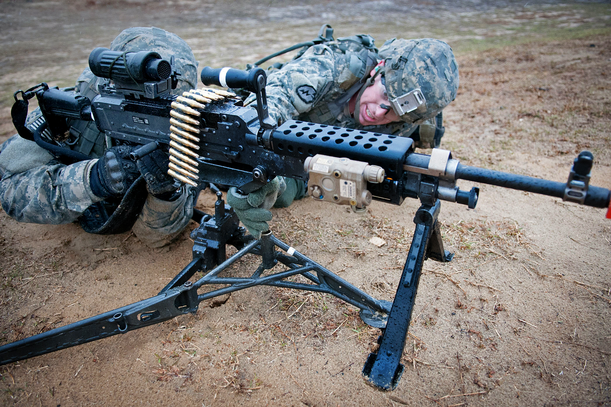 Army Spc. Benjamin Clement, right, helps Army Spc. Antonio Esparza, place a  M240B machine gun on