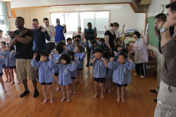Marines with Marine Aviation Logistics Squadron 12 and Marine Aircraft Group 12 do the 'Head, Shoulders, Knees and Toes' dance with the children of the Marifu Hoikuen (Marifu pre-school/kindergarten) during a community relations event March 14, 2013. Before the volunteers danced with the children, they passed out certificates to those students advancing to the next grade level.