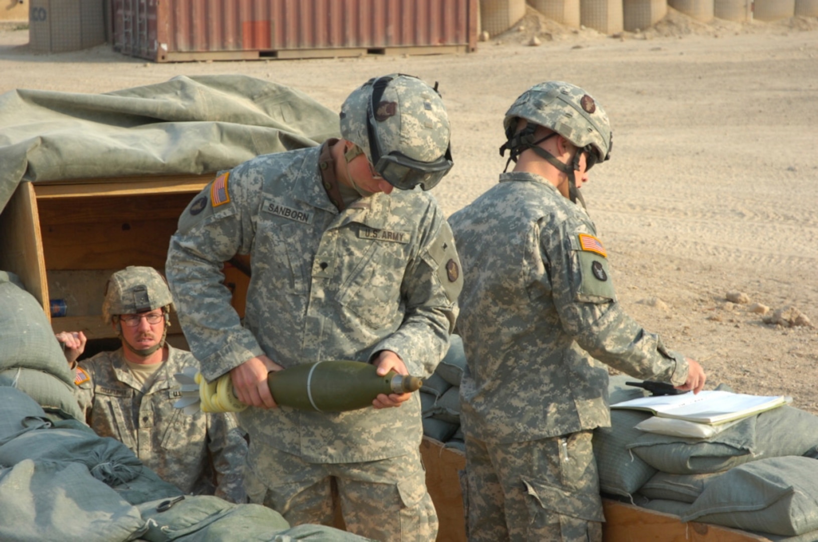 Spc. Anthony Sanborn of Alexandria, Minn., (center) checks the fuse setting of a 120 millimeter mortar as Spc. Steven Luitjens of St. Cloud, Minn., (right) tells him which setting to use during a drill earlier this month at Camp Fallujah, Iraq. Spc. Chris Colliflower of Roseau, Minn., is at the left. All Soldiers are from Company B, 2nd Battalion, 136th Combined Arms Battalion, 1st Brigade Combat Team, 34th Infantry Division.