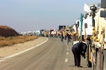 Semi trucks and trailers escorted by Soldiers of Company B, 1st Battalion, 133rd Infantry, 1st Brigade Combat Team, 34th Infantry Division, stretch for several miles during a security halt on Nov. 27 on this road in western Iraq.