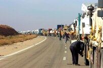Semi trucks and trailers escorted by Soldiers of Company B, 1st Battalion, 133rd Infantry, 1st Brigade Combat Team, 34th Infantry Division, stretch for several miles during a security halt on Nov. 27 on this road in western Iraq.