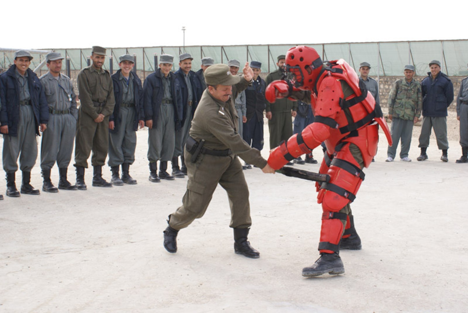 Two senior Afghan policemen demonstrate the proper use of a baton to subdue suspects. New recruits as well as policemen in the Transitional Integration Course receive instruction on the proper use of force and human rights during their training at the regional training center.