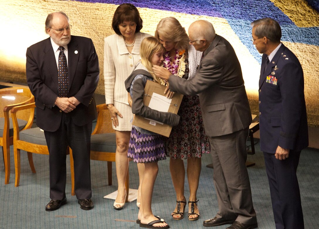 HONOLULU - Jennifer and Victoria Riddick, wife and daughter of Master Sgt. Travis Riddick, hold back tears as they accept the Hawaii Medal of Honor on his behalf during a ceremony, March 27, 2013 at the Hawaii state Capitol. (U.S. Marine Corps photo by Lance Cpl. Nathan Knapke)