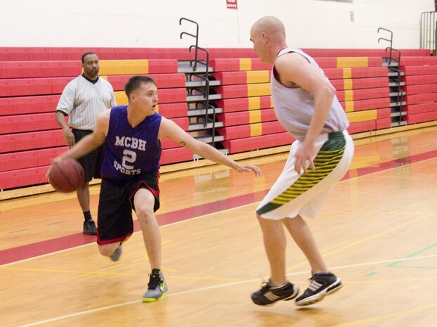 MARINE CORPS BASE HAWAII - Headquarters Battalion shooting guard Julio Delacruz tries to manuever the ball past a Postal player during an intramural basketball game at the Semper Fit Center gym, March 27, 2013. The intramural basketball season came to a close with a brutal tug of war between Headquarters Bn. and Postal, resulting in Headquarters Bn.’s win, 43-37. (U.S. Marine Corps photo by Kristen Wong)