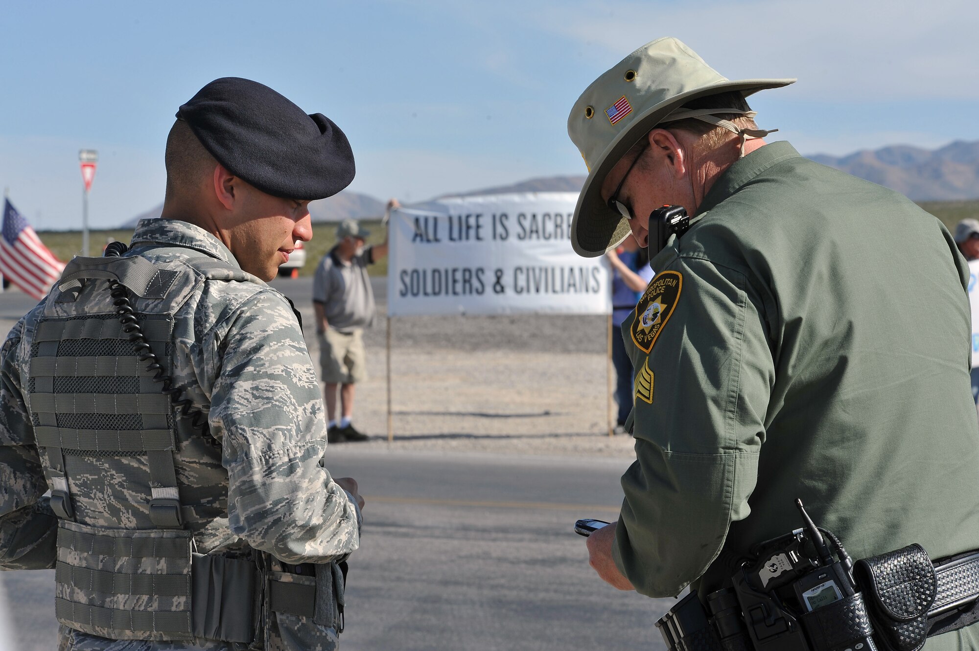 INDIAN SPRINGS, Nev. – 799th Security Forces Squadron and local law enforcement observe demonstrators during a protest, March 29, 2013. Military and civilian law enforcement agencies partner together to help ensure the safety of Airmen while also protecting the First Amendment rights of U.S. citizens. (U.S. Air Force photo by Senior Master Sgt. P.H./Released)