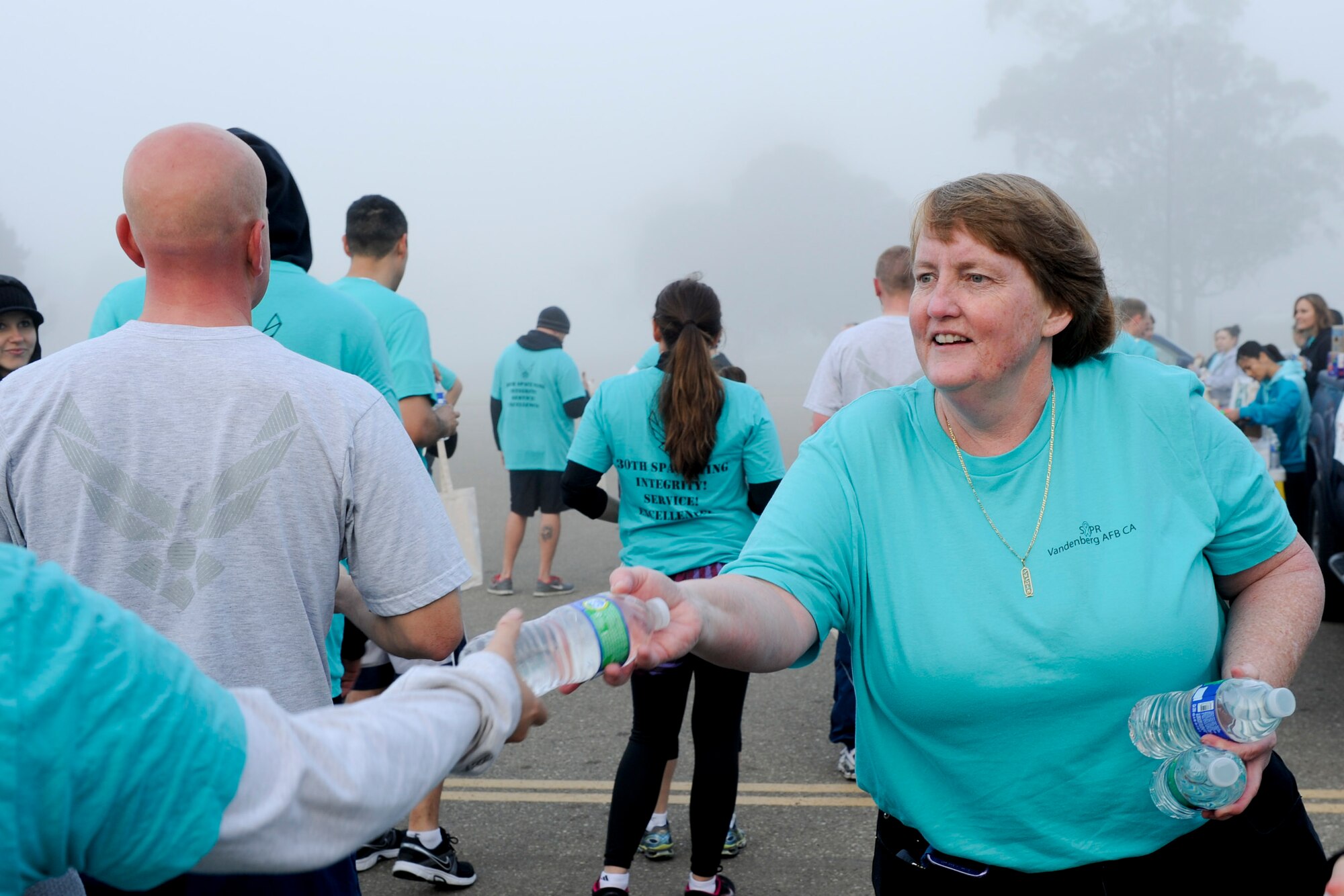 VANDENBERG AIR FORCE BASE, Calif. -- Donna Rathbun, the 30th Space Wing sexual assault response coordinator, hands out water during the monthly Fit-to-Fight Run here Friday, March 29, 2013. Runners were encouraged to wear blue and teal T-shirts, representing Child Abuse Awareness Month and Sexual Assault Awareness Month respectively. (U.S. Air Force photo/Staff Sgt. Levi Riendeau)

