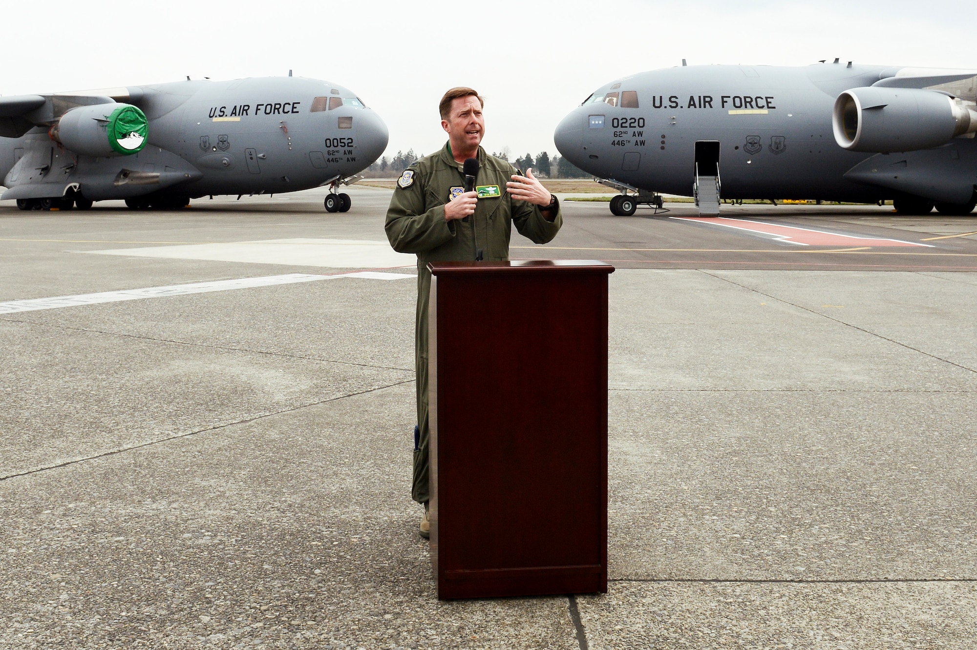 Col. Wyn Elder, 62nd Airlift Wing commander, addresses an audience March 27, 2013, during a C-17 Globemaster III delivery ceremony at Joint Base Lewis-McChord, Wash. The ceremony took place shortly after McChord Field's newest and final C-17 (right) landed, and featured McChord's first C-17 (left) which was delivered to the base July 30, 1999. (U.S. Air Force photo/Tech. Sgt. Sean Tobin)