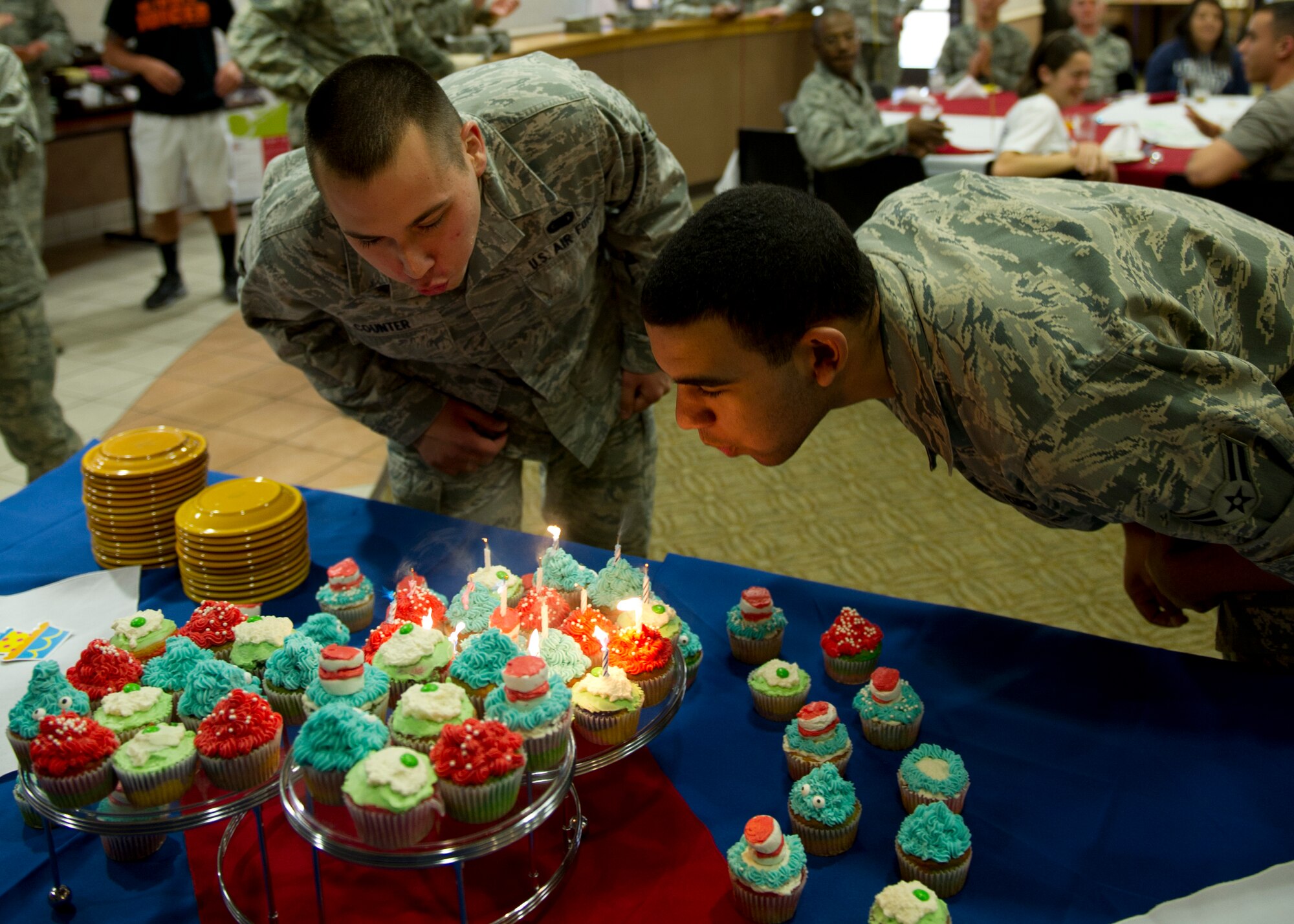 Airmen 1st Class Andrew Caine and Thomas Counter blow out candles on cupcakes during the first quarter birthday meal celebration at the Shifting Sands Dining Facility at Holloman Air Force Base, N.M., March 28. Caine is a 49th Comptroller Squadron customer service technician and Counter is a 49th Logistics Readiness Squadron equipment manager. Airmen born between the months of January and March were invited to attend the celebration. (U.S. Air Force photo by Senior Airman Kasey Close/Released)