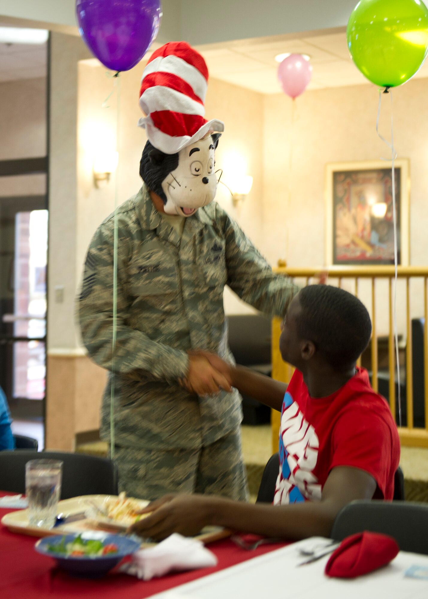 Command Chief Master Sgt. James Patrie, 49th Wing command chief, wishes an Airman a happy birthday while wearing a Dr. Seuss “Cat in the Hat” mask during the first quarter birthday meal celebration at the Shifting Sands Dining Facility at Holloman Air Force Base, N.M., March 28. This quarter’s birthday celebration theme was Dr. Seuss in light of his birthday which was also during the quarter. (U.S. Air Force photo by Senior Airman Kasey Close/Released)