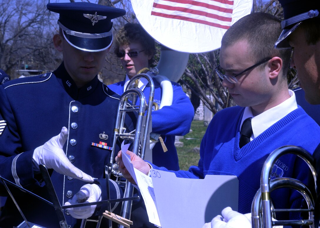 A member of The Wynford High School Band hands Tech. Sgt. William Timmons, U.S. Air Force Band member, a piece of sheet music March 23, 2013, at Congressional Cemetery in Washington, D.C. The bands paid tribute to composer John Philip Sousa during a combined performance where some of the composer's most-famous marches were played in front of his gravesite. (U.S. Air Force photo/Senior Airman Lindsey A. Porter)