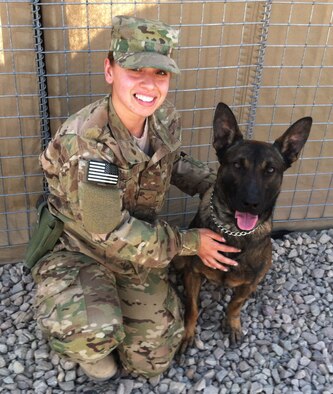 Senior Airman Victoria Hill, 445th Communications Air Expeditionary Advisory Squadron, poses with Dex, an American K-9, during her six-month deployment to Shindand Air Base, Afghanistan, Oct. 25, 2012.  Hill volunteered to wear a full-body suit to help the K-9s practice for real-world situations. (Courtesy photo/Released)