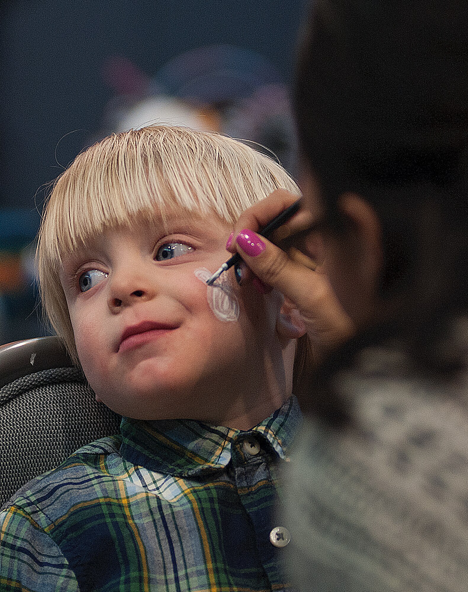 James Thompson, 2, has his face painted by Vanessa Gomez at the F. E. Warren Spring Carnival in the Fall Hall Community Center March 23. Thompson is the child of Sarah and Airman 1st Class Joshua Thompson, 90th Missile Security Forces Squadron. (U.S. Air Force photo by R.J. Oriez)