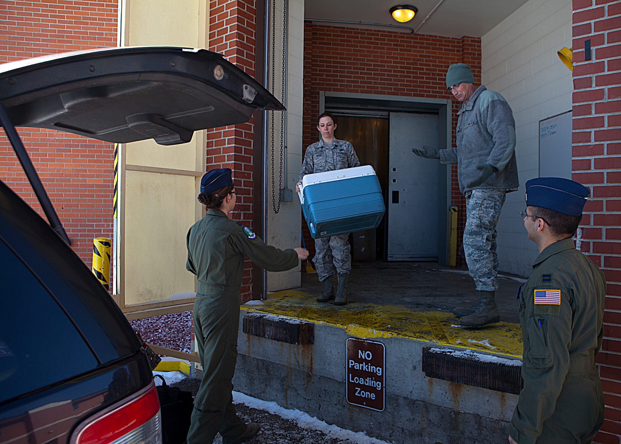 Staff Sgt. Kimberly Wood, 90th Operation Support Squadron, hands the missile alert facility and Feeding Operations cooler containing food to restock the missile alert facility kitchen to Capt. Caitlin Olson, 321st Missile Squadron ICBM combat crew commander. (U.S. Air Force photo by 2nd Lt. Christen Downing)