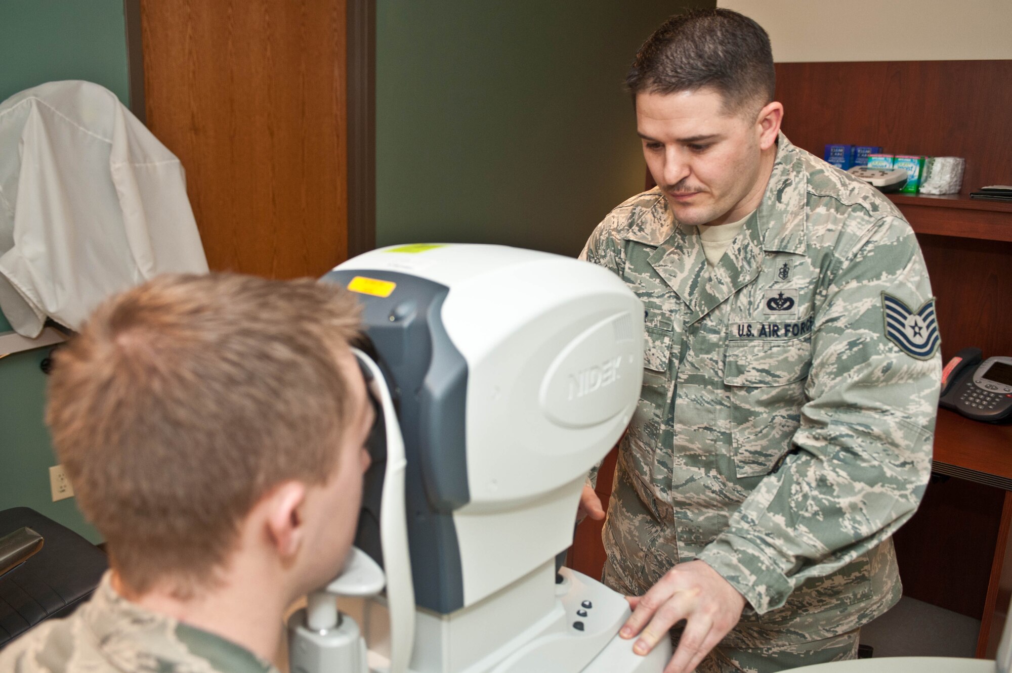 Tech. Sgt. Mark Slater, 28th Medical Operations Squadron optometry NCO in charge, sets up an auto-refractor to examine Airman 1st Class Charles Wood, 28th MDOS patient travel administrator, during a health evaluation at Ellsworth Air Force Base, S.D., March 15, 2013. The optometry clinic is responsible for administering eye exams, issuing corrective lenses, acting as a liaison for optical surgeries and similar optical services to Airmen and their families at Ellsworth. (U.S. Air Force photo by Airman 1st Class Zachary Hada/Released)