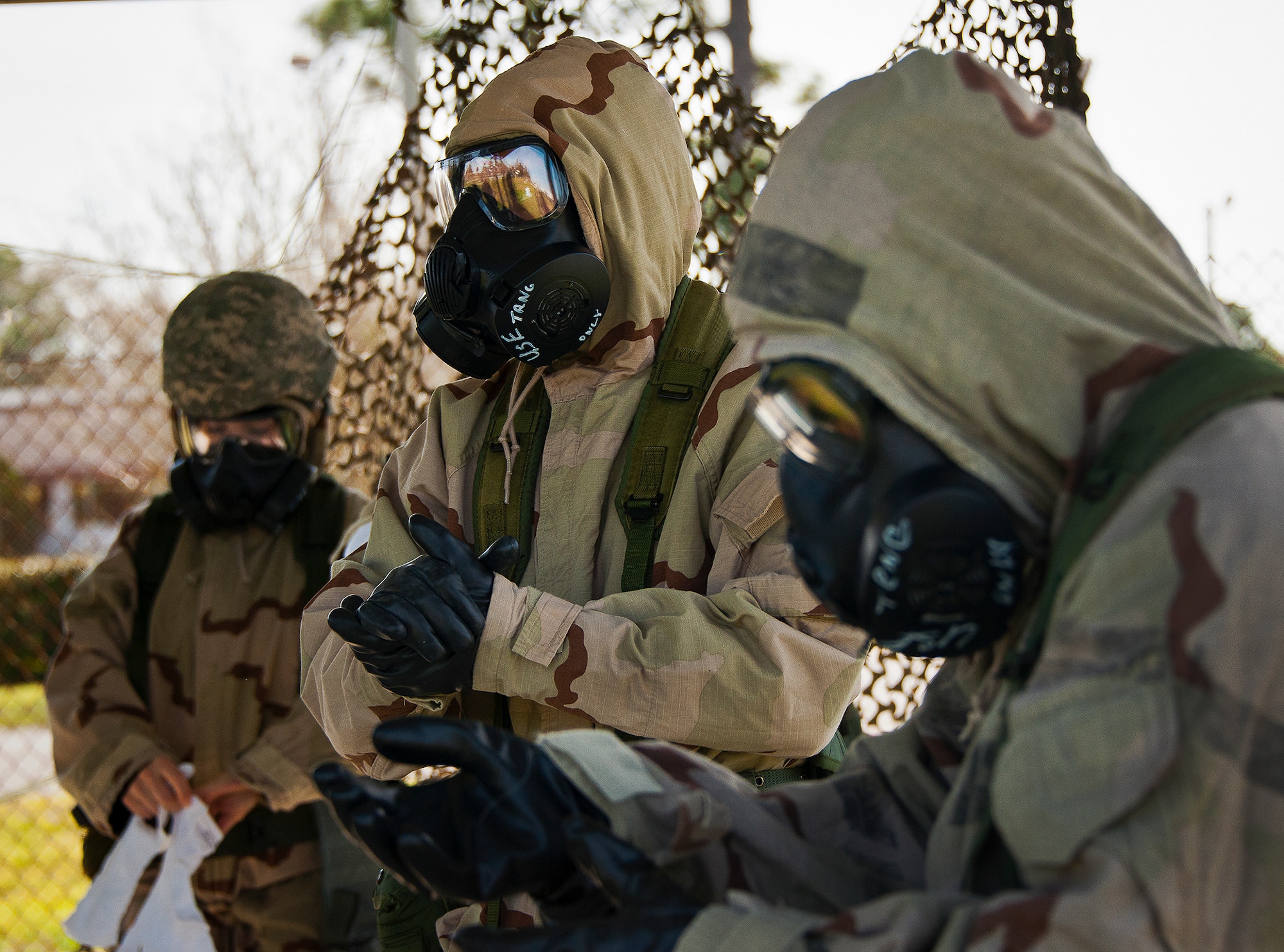 Airmen put on protective gloves as part of their transition to MOPP-4 gear during the field training portion of a Phase II exercise March 21 at Eglin Air Force Base, Fla. A Phase II evaluates a unit's ability to meet wartime and contingency taskings of employing the force, sustaining the force and the ability to survive and operate.  More than 75 deployers, in two groups, received classroom and practical field training over March 20-21 to meet the readiness requirement.  (U.S. Air Force photo/Samuel King Jr.) 
