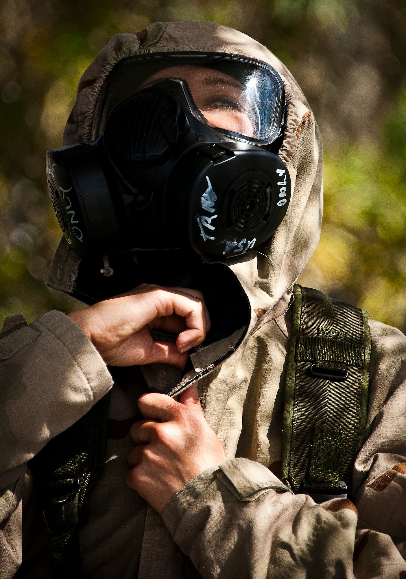 An Airman seals her neck area after hearing the alert to go to MOPP-4 gear during the field training portion of a Phase II exercise March 21 at Eglin Air Force Base, Fla. A Phase II evaluates a unit's ability to meet wartime and contingency taskings of employing the force, sustaining the force and the ability to survive and operate.  More than 75 deployers, in two groups, received classroom and practical field training over March 20-21 to meet the readiness requirement.  (U.S. Air Force photo/Samuel King Jr.) 