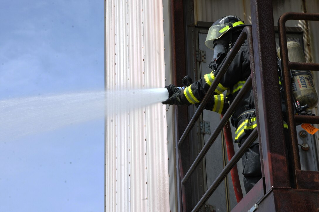 George Hernandez, Naval Base Guam Fire and Emergency Services  firefighter, sets the nozzle pattern before entering the training facility during a structural fire exercise on Andersen Air Force Base, Guam, March 27, 2013. Andersen Fire and Emergency Services personnel hosted four Saipan fire officers for joint fire training during their visit to Guam March 25-29. (U.S. Air Force photo by Airman 1st Class Emily A. Bradley/Released)