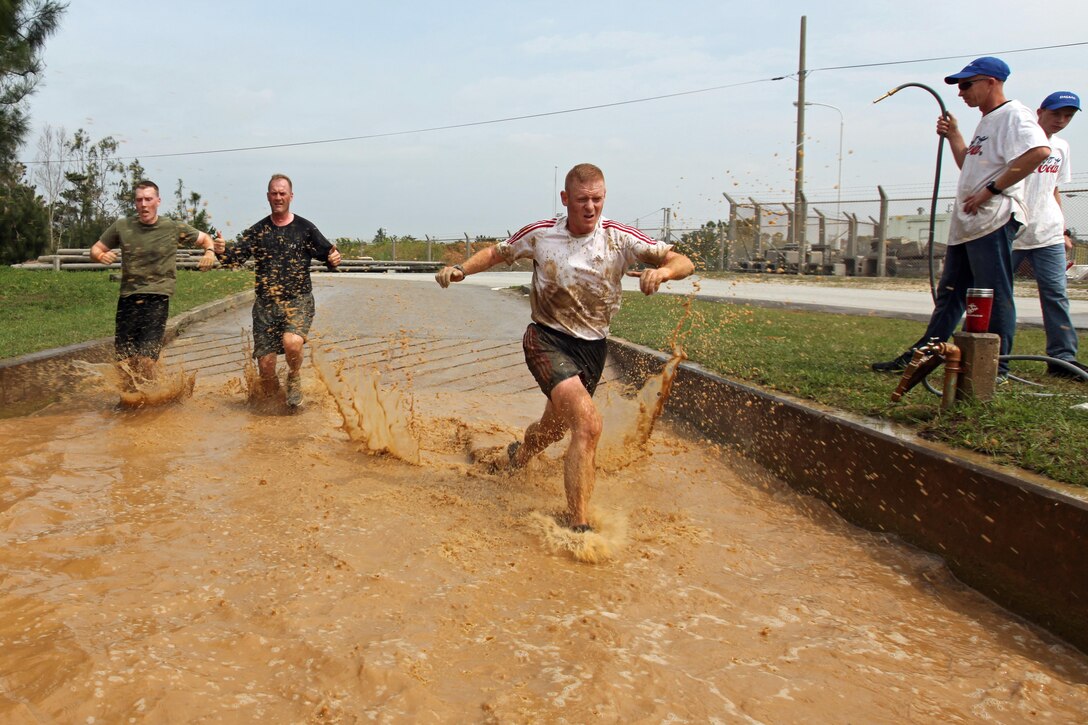 Marines with the command element of the 31st Marine Expeditionary Unit wade through a water obstacle during the 10K mud run here, March 30. Hundreds of competitors from all over the island gathered to participate in the run, which was put together by Marine Corps Community Services and the Single Marine Program. The run included obstacles that required runners to wade through shin-deep water, scale a five foot wall, and traverse thick patches of mud.