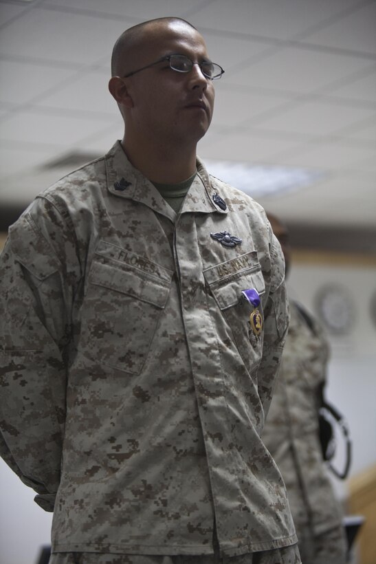 Petty Officer 1st Class Benny Flores stands before a crowd after receiving a Purple Heart at a ceremony at Camp Leatherneck, Afghanistan, Dec. 22, 2012. Flores provided lifesaving medical care to Marines and Afghan Uniform Police during an enemy attack, despite his own serious injuries, while serving as a field service medical technician during combat operations in Nimruz province's Zaranj district during a partnered convoy, April 28, 2012. Flores will be awarded a Silver Star for his heroic actions at a ceremony at the 1st Air Naval Gunfire Liaison Company aboard Camp Pendleton, Calif. May 3, 2013. (Photo Courtesy of Petty Officer 1st Class Benny Flores)