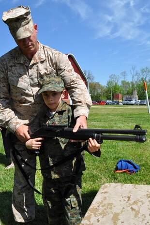 Capt. Jason Latta of Programs helps his son, Jack, with a weapon at the Infantry Combat Equipment display April 25 during Marine Corps Systems Command's "Bring Your Daughters and Sons to Work Day." 