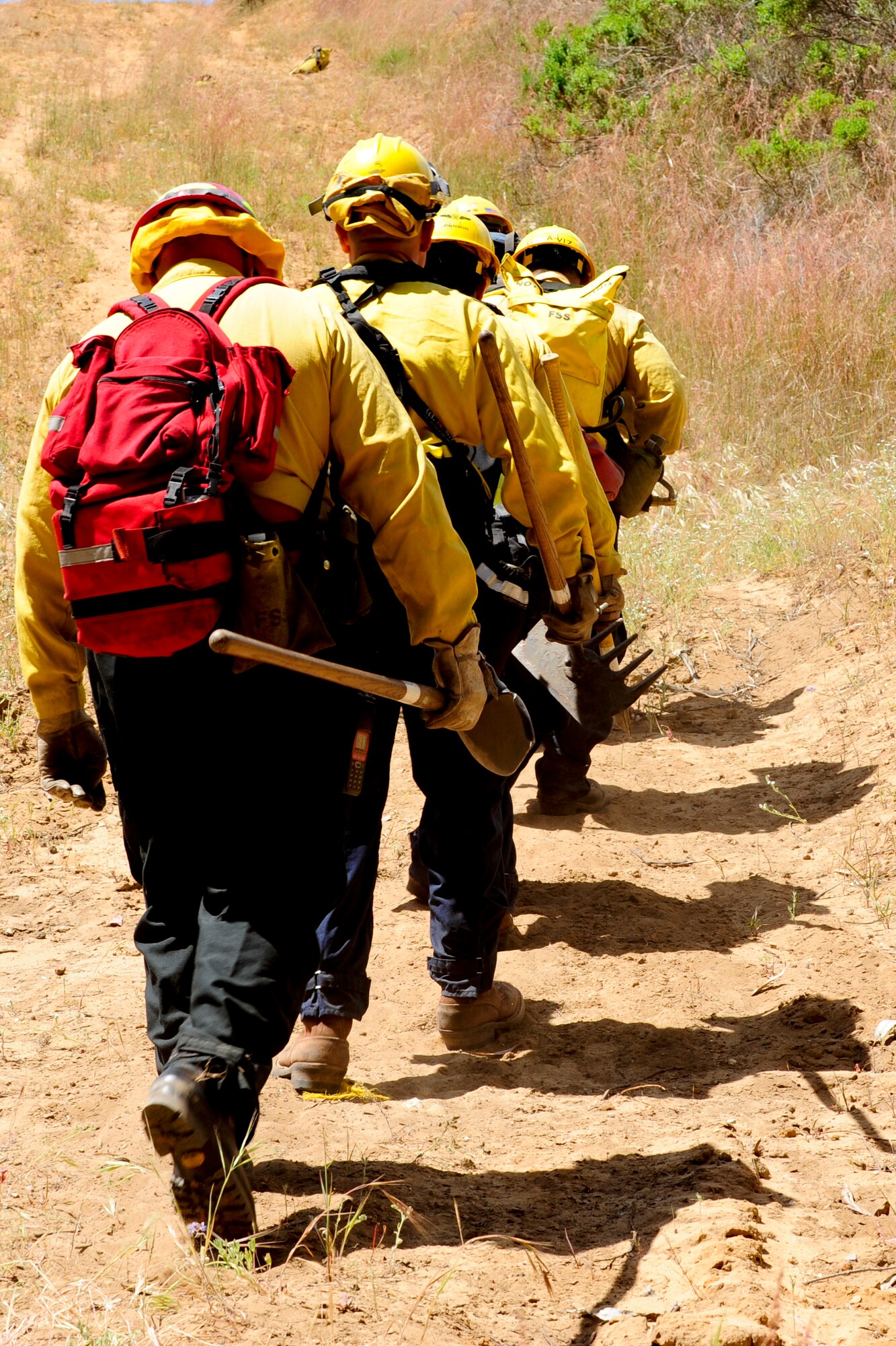 VANDENBERG AIR FORCE BASE, Calif. – 30th Civil Engineer Squadron firefighters move uphill armed with axes, shovels, and rakes during training here Tuesday, April 30, 2013. The firefighters were participating in Vandenberg’s Annual Wildland Fire Academy, which is designed to keep Team V’s firefighters mission ready. (U.S. Air Force photo/Airman Yvonne Morales)
