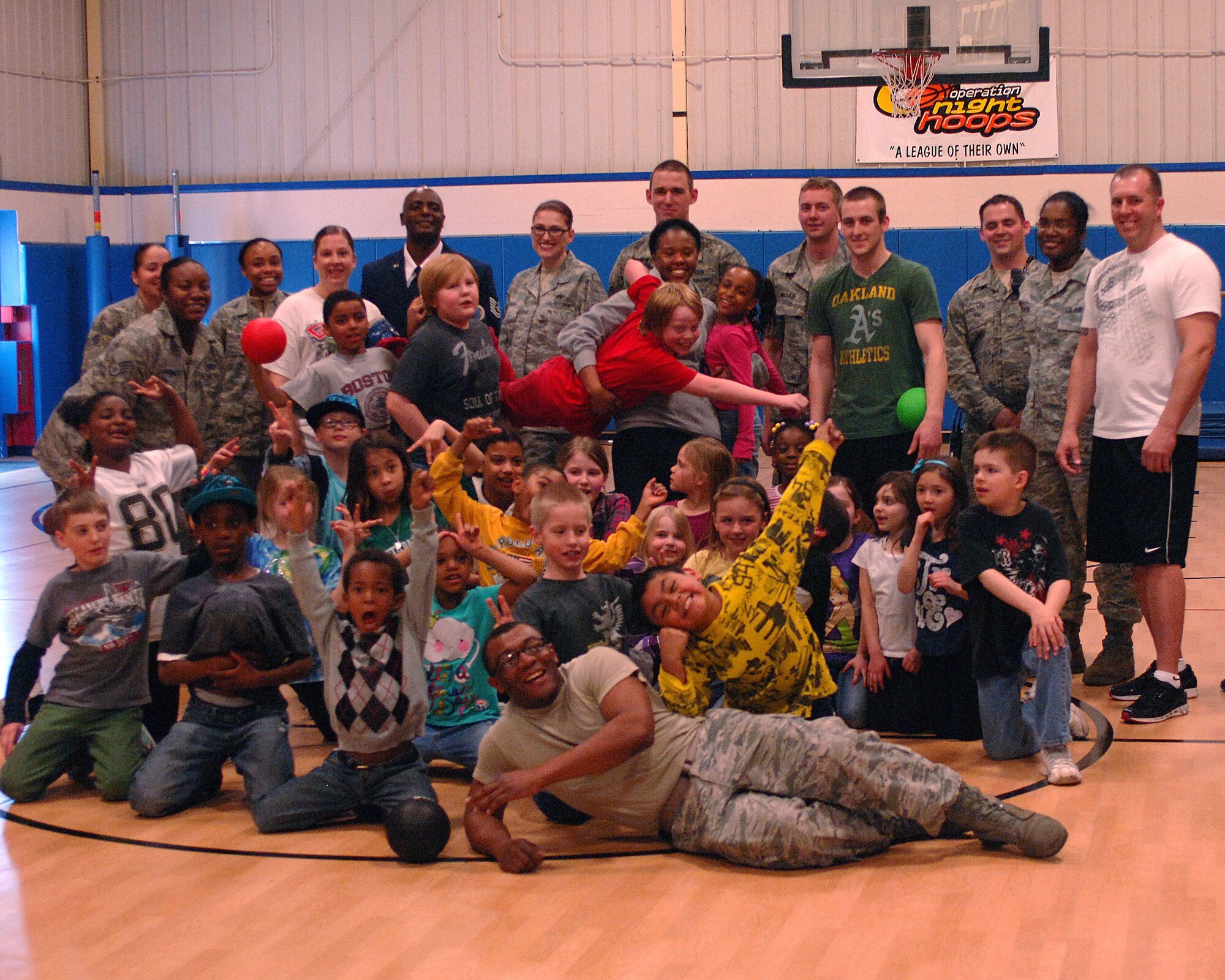Members of the Grand Forks Air Force Base, N.D., Youth Center and volunteers pose together after their first round of dogeball at the Youth Center, April 26, 2013. Volunteers helped serve pizza at the event before participating in dodge ball matches. The fun-filled event was part of the base's observance of this year's Month of the Military Child. (U.S. Air Force photo/Airman 1st Class Zachiah Roberson)