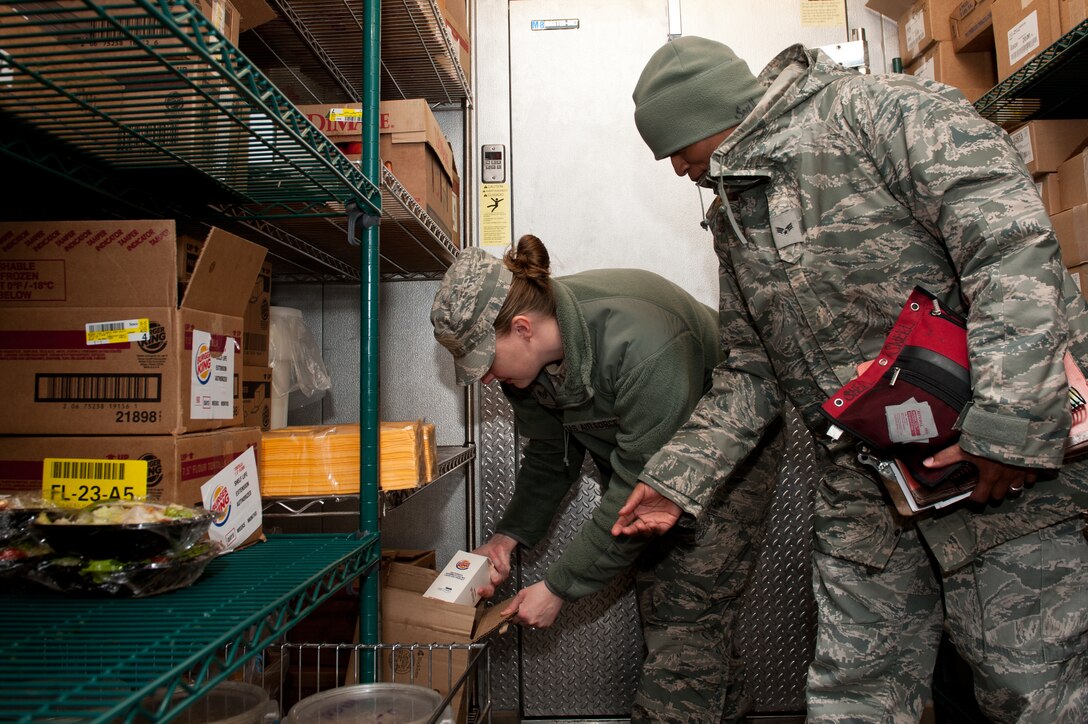 Staff Sgt. Ellie Dierkhising, 28th Medical Operations Squadron flight medicine independent medical technician, and Senior Airman Sylvester Snell, 28th MDOS public health technician, verify expiration dates on dairy products during a health inspection at the Exchange food court on Ellsworth Air Force Base, S.D., April 18, 2013. Public Health Airmen are dedicated to maintaining a healthy environment by preventing disease and providing services to the Ellsworth community. (U.S. Air Force photo by Airman 1st Class Kate Thornton-Maurer/Released)