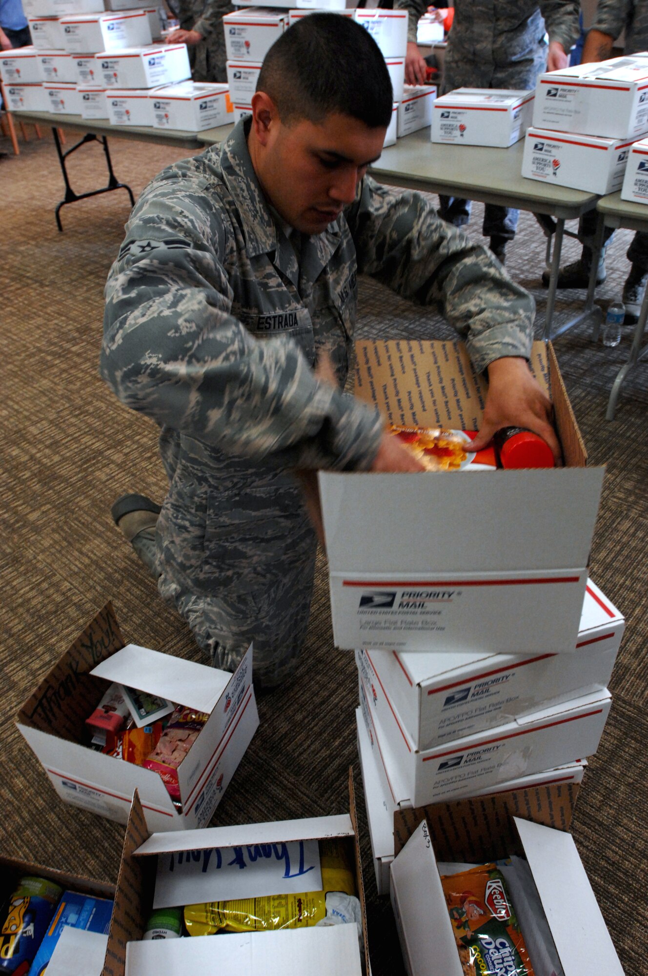 Airman 1st Class Maximiliano Estrada, 319th Force Support Squadron, assembles care packages for deployed troops April 27, 2013, in Grand Forks city. About a dozen service members from Grand Forks Air Force Base, N.D., teamed up with the mayor’s office and 35 members of the Grand Forks Youth Commission packed nearly 200 boxes of goods, totaling about $5,500 in value, to be received by about 90 deployed active-duty Airmen and a dozen North Dakota Air National Guardsmen. (U.S. Air Force photo/Staff Sgt. Susan L. Davis)