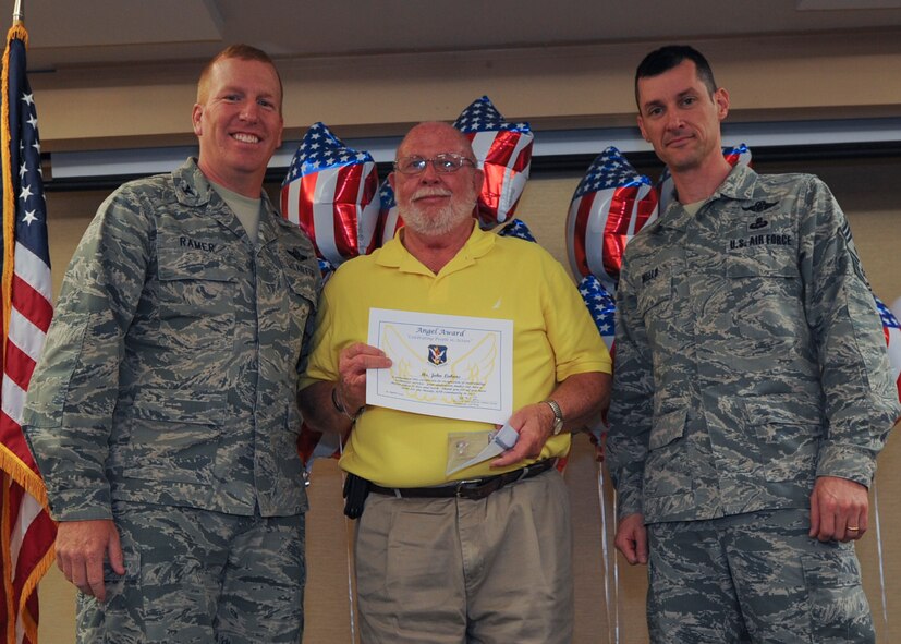 U.S. Air Force Col. Steve Ramer, 23d Wing vice commander, and Chief Master Sgt. Matthew Wells, 23d WG command chief, present the Angel Award to John Lukens during the 2013 Volunteer Recognition Ceremony at Moody Air Force Base, Ga., April 25, 2013. Lukens was given the Angel Award for the most volunteer hours spent improving the quality of life for military communities. (U.S. Air Force photo by Senior Airman Eileen Meier/Released)