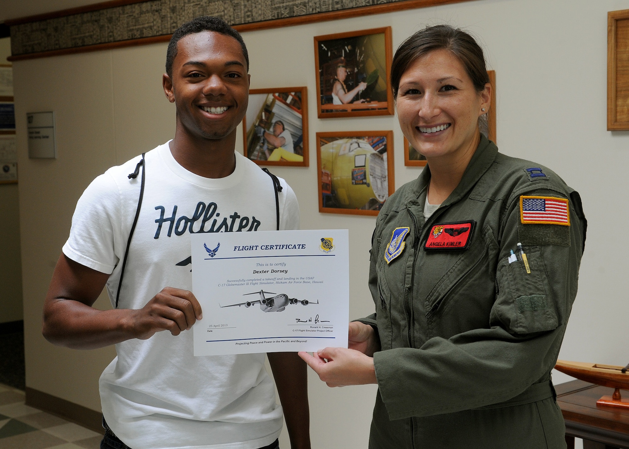 Radford High School junior, Dexter Dorsey, accepts a flight certificate from Capt. Angela Kimler, 535th Airlift Squadron training flight commander and Radford High School alumna, during a career-day program at the C-17 Flight Simulator building, Joint Base Pearl-Harbor-Hickam, Hawaii, April 25, 2013. Dorsey and his fellow classmates received the certificates for successfully completing a takeoff and landing in a C-17 Globemaster III Flight Simulator.  (U.S. Air Force photo/Tech. Sgt. Jerome S. Tayborn)