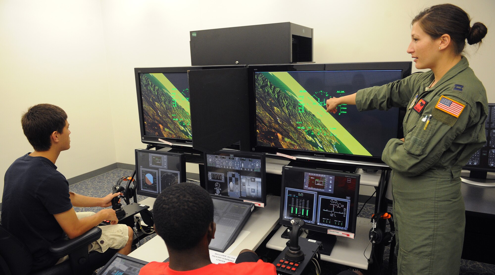 Radford High school juniors, Andrew Davis, left, and Torey Bowman, center, receive flight instructions while on a C-17 Globemaster III reconfigured desktop simulator from Capt. Angela Kimler, 535th Airlift Squadron training flight commander and Radford High School alumna, during a career day at Joint Base Pearl-Harbor-Hickam, Hawaii, April 25, 2013. The purpose of the event was to offer possible recruits a glimpse of daily duties performed by Airmen. (U.S. Air Force photo/Tech. Sgt. Jerome S. Tayborn)