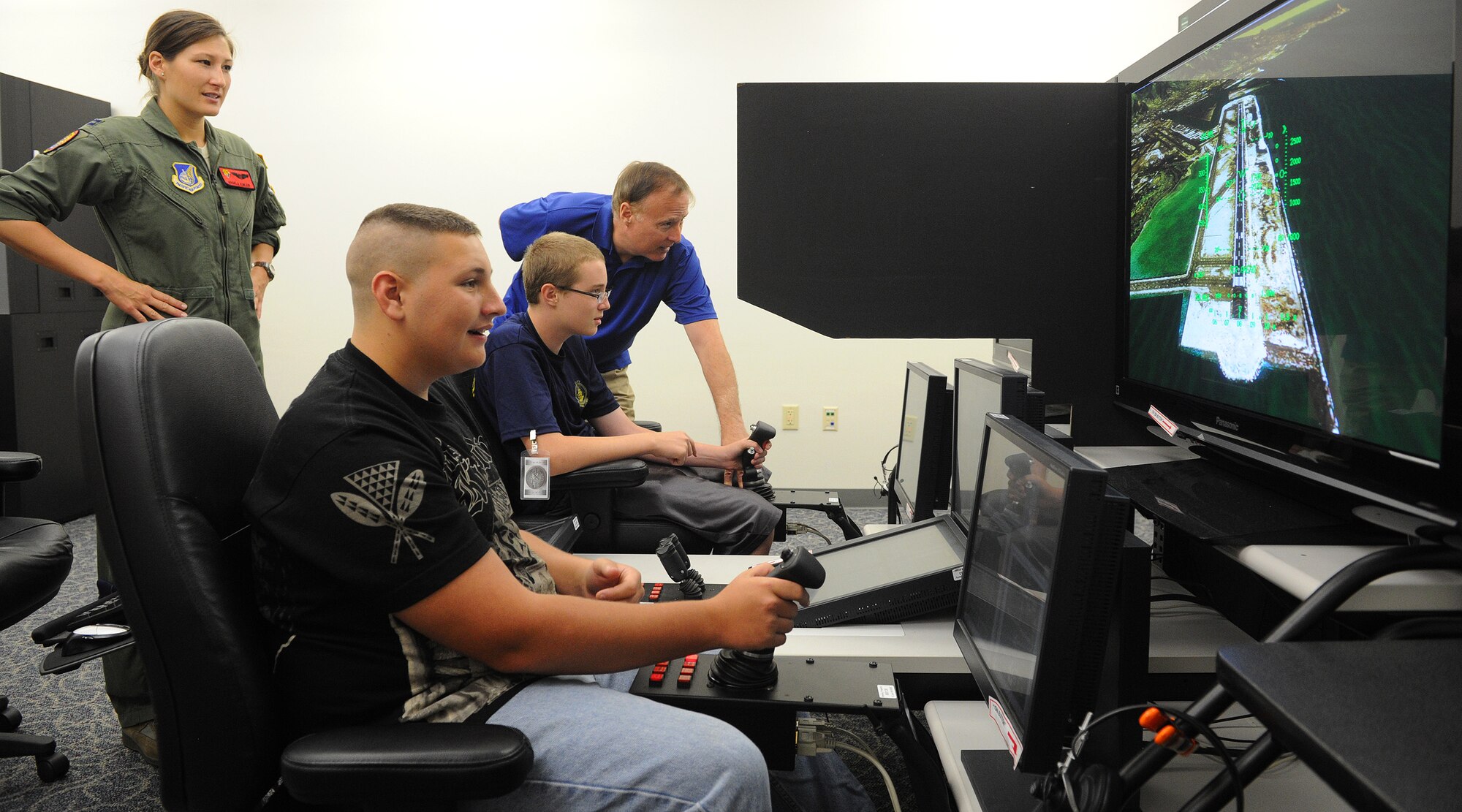 Capt. Angela Kimler, 535th Airlift Squadron training flight commander and Radford High School alumna, watches as Ron Cressman, 15th Operations Support Squadron C-17 flight simulator project officer, gives landing instructions to Radford High School juniors, Brad Woodward and Gary Sells, as they prepare to land a C-17 Globemaster III reconfigured desktop simulator during career day at Joint Base Pearl-Harbor-Hickam, Hawaii, April 25, 2013. The students are expected to investigate the world of work and be exposed to a variety of careers so they can make informed career decisions. (U.S. Air Force photo/Tech. Sgt. Jerome S. Tayborn)