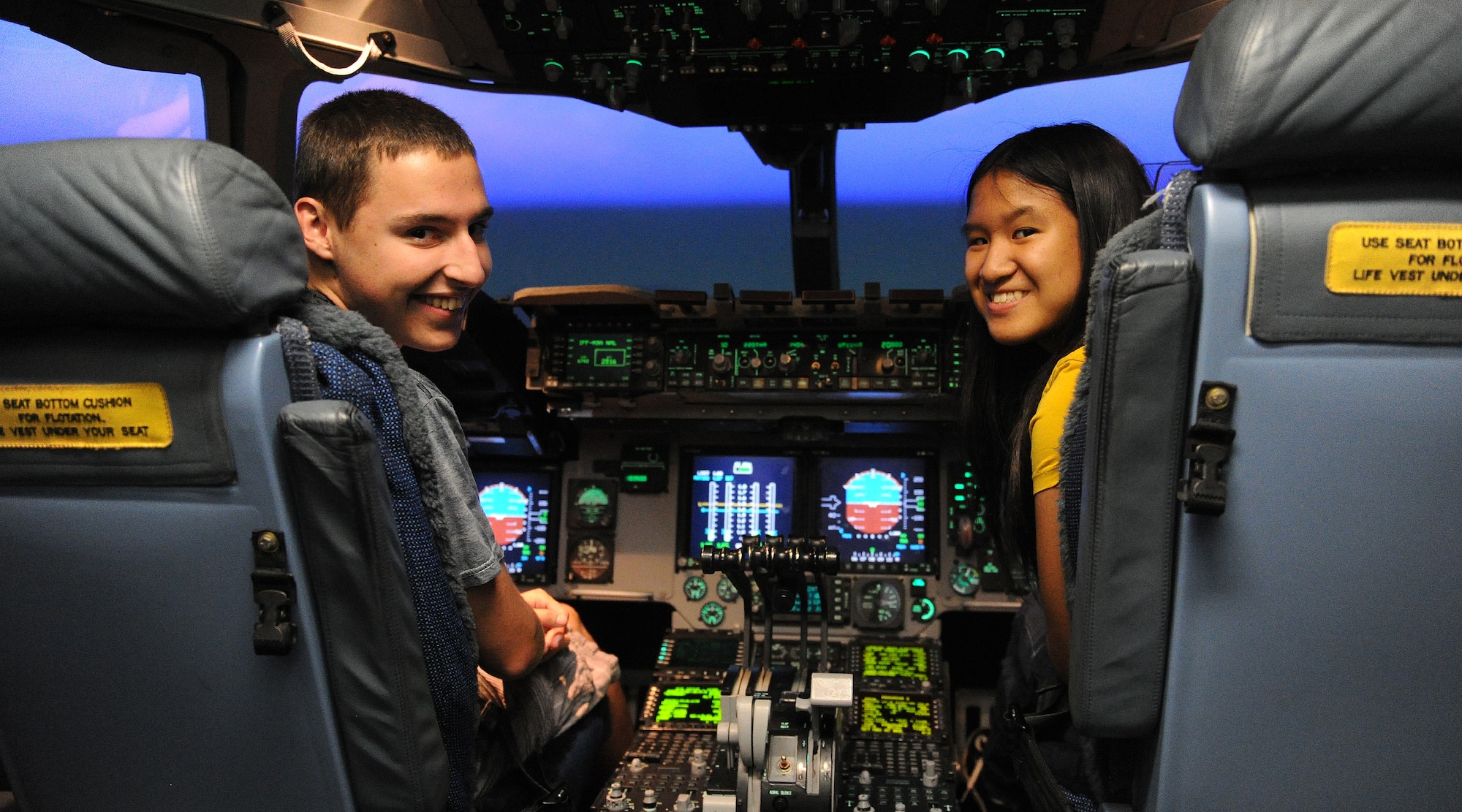 Radford High School juniors, Derek Franklin, left, and Ashley Kawewehi Antonio, right, sit in the pilot seats of the C-17 Globemaster III simulator during a career day at Joint Base Pearl Harbor-Hickam, Hawaii, April 25, 2013. The purpose of the career day is to expose students to a variety of career fields in effort to encourage and motivate them to continue their education and pursue a profession they are passionate about. (U.S. Air Force photo/Tech. Sgt. Jerome S. Tayborn)