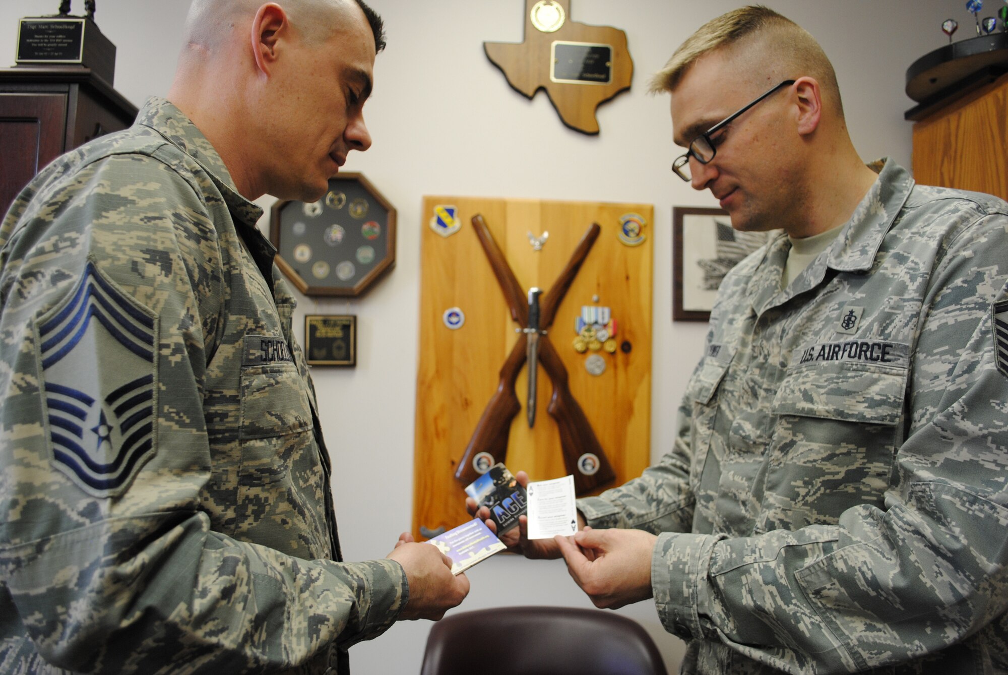 (Right) Master Sgt. Derek Power, 319th Medical Operations Squadron Mental Health flight chief, shows the 319th Medical Group superintendent, Chief Master Sgt. Marc Schoellkopf, a new stack of Air Force ACE suicide prevention program cards on April 25, 2013, at Grand Forks Air Force Base, N.D.  Power was selected as the base’s Warrior of the Week for the first week of May 2013. (U.S. Air Force photo/Staff Sgt. Luis Loza Gutierrez)