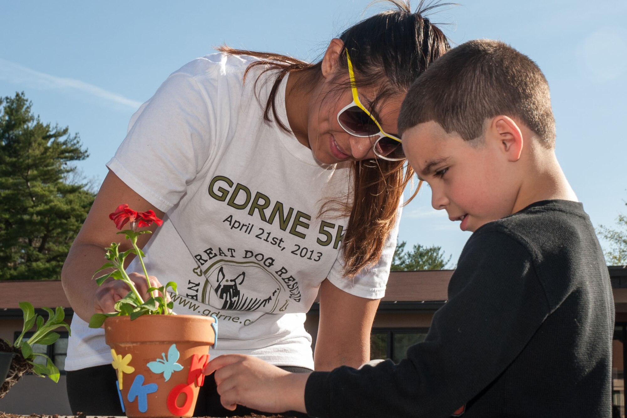 HANSCOM AIR FORCE BASE, Mass -- Christina Benitez (left) assists Kenneth Cerezo in decorating a flower pot at the Hearts Apart Spring Fling April 24. The Hearts Apart program offers support and activities for families with deployed loved ones. For more information on the program contact the Airman and Family Readiness Center at 781-377-4222. (U.S. Air Force photo by Mark Herlihy)