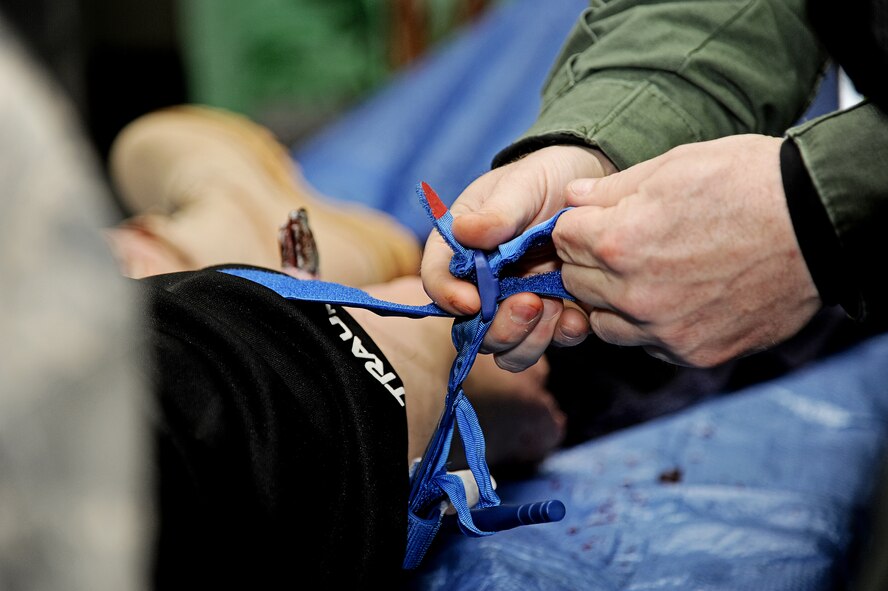 A tactical operator, part of the Illinois Special Weapons and Tactics team, applies a tourniquet to a mannequin during training April 24, 2013 in Collinsville, Ill. Lt. Col. Rance Bryan, Center for Sustainment and Readiness Trauma Skills critical care trauma instructor, trained SWAT team members on the proper way to apply a tourniquet to a limb that was bleeding profusely.  The mannequin is very life-like, helping those being trained to get a feel for how it would be to apply a tourniquet on a real person. (U.S. Air Force photo/Airman Kristina Forst)