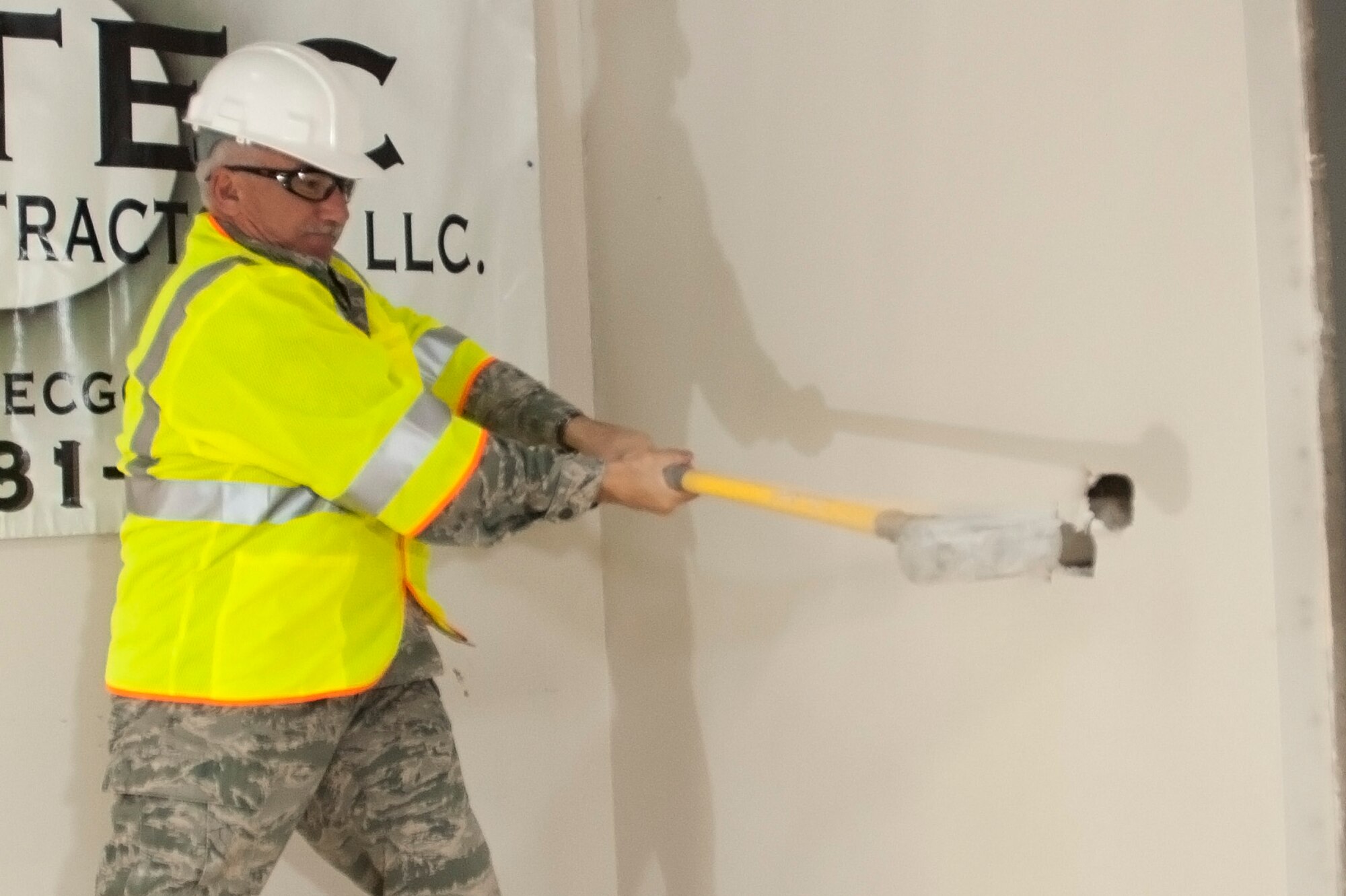 Air National Guard Chief Master Sgt. Philip Mabie, security forces manager, 140th Security Forces Squadron, takes a swing at one of the old walls in building 700 in order to kick off building renovations for what will soon be their new office space. (U.S. Air National Guard photo by Tech. Sgt. Wolfram Stumpf)