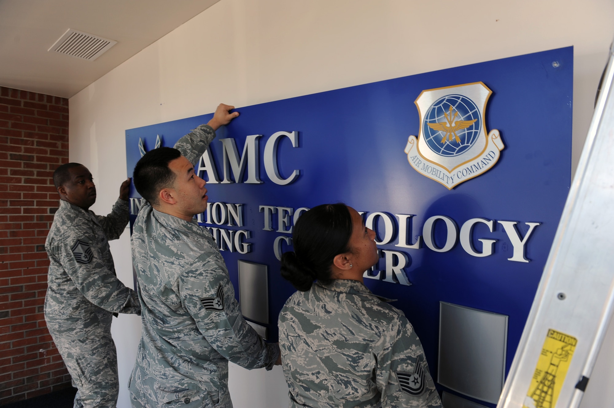 Senior Master Sgt. Aldo Adams, Air Mobility Command A6 Command Force Development superintendent, Staff Sgt. David Yu, Cyber Training Center instructor, and Tech. Sgt. Maylene Little, Cyber Technology Training Center NCOIC, remove the CTTC sign April 30. The CTTC closed May 1.  The training function will now fall under 375th Communication Squadron. (U.S. Air Force photo/Airman 1st Class Josh Eikren)
