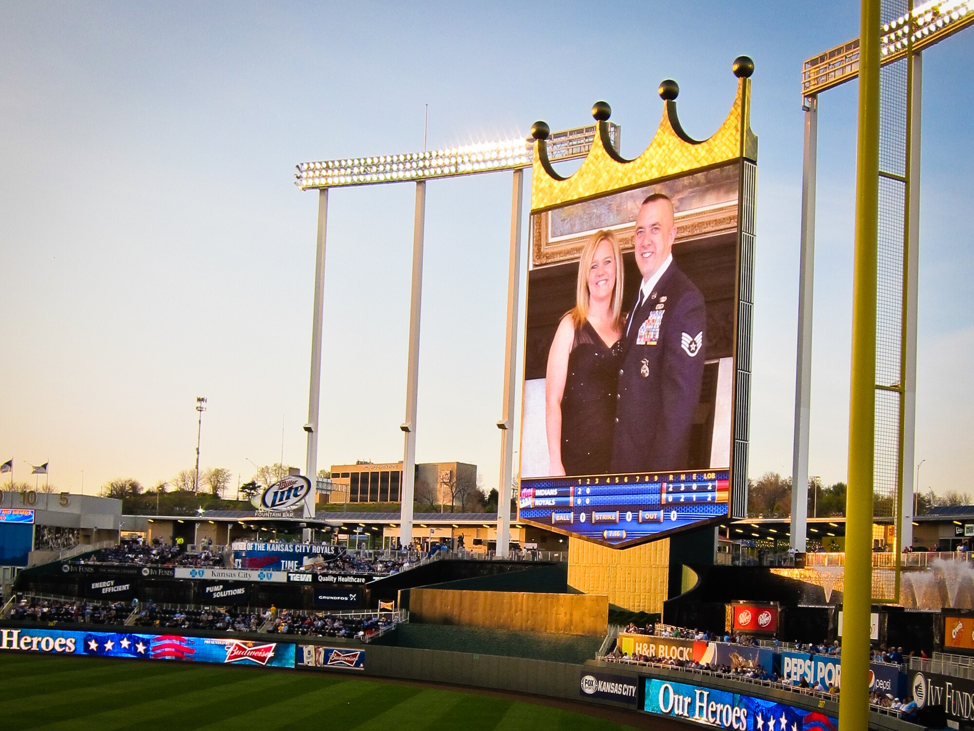 A photo of U.S. Air Force Staff Sgt. Troy Green, a squad leader with the 139th Security Forces Squadron, Missouri Air National Guard, and his wife, is displayed on a massive TV at Kauffman Stadium in Kansas City, Mo., April 28, 2013. The Kansas City Royals honored Green who received the Purple Heart for his actions while deployed to Afghanistan in 2012. (U.S. Air National Guard photo by Tech. Sgt. Michael Crane/Released)