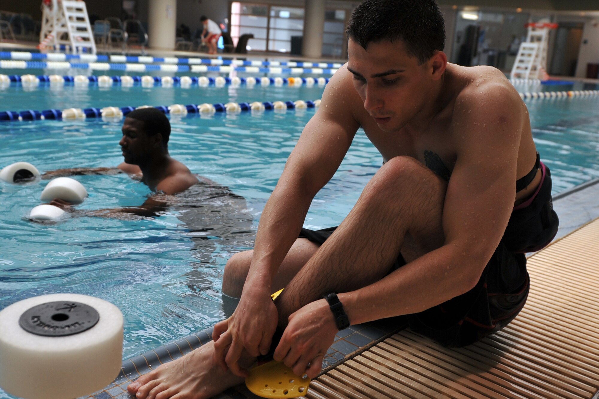 Staff Sgt. Mark Olsen, 51st Medical Group bioenvironmental technician, puts on an ankle fin during a water-jogging class at the base pool on Osan Air Base, Republic of Korea, April 29, 2013. The strap added resistance while he ran, increasing the effort he used throughout the workout. (U.S. Air Force photo/Senior Airman Alexis Siekert)