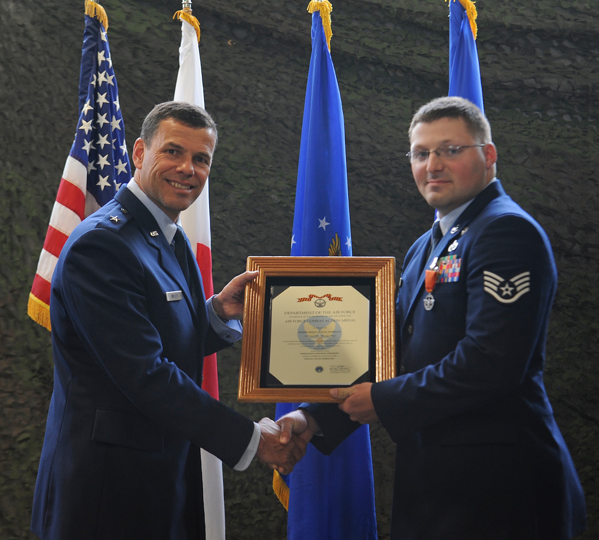 U.S. Air Force Staff Sgt. Craig Zehrbach (right), 18th Civil Engineer Squadron explosive ordinance disposal technician, receives the Combat Action Medal from Brig. Gen. Matt Molloy (left), 18th Wing commander, on Kadena Air Base, Japan, April 30, 2013. Zehrbach was awarded the medal for his actions during Operation Enduring Freedom. With the help of Staff Sgt. Michael Vallejo, 18th CES EOD technician, they were able to provide combat life-saving procedures to a wounded Polish solider and drag him to safety. (U.S. Air Force photo by Airman 1st Class Malia Jenkins/Released)