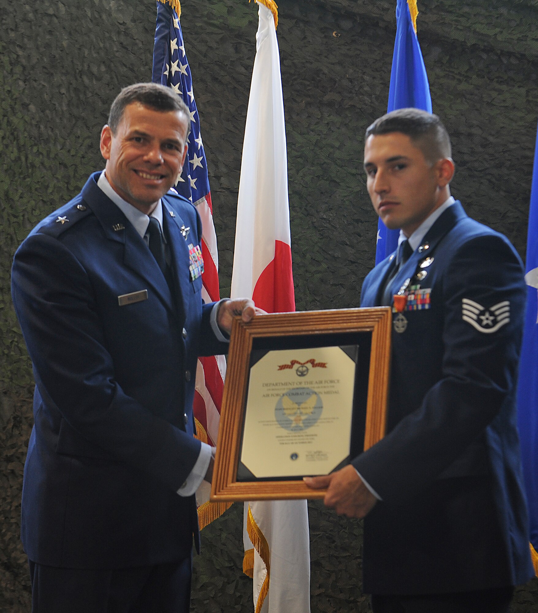 U.S. Air Force Staff Sgt. Michael Vallejo (right), 18th Civil Engineer Squadron explosive ordinance disposal technician, receives the Combat Action Medal from Brig. Gen. Matt Molloy (left), 18th Wing commander, on Kadena Air Base, Japan, April 30, 2013. Vallejo was awarded the medal for his actions during Operation Enduring Freedom. With the help of Staff Sgt. Craig Zehrbach, 18th CES EOD technician, they were able to provide combat life-saving procedures to a wounded Polish solider and drag him to safety. (U.S. Air Force photo by Airman 1st Class Malia Jenkins/Released) 