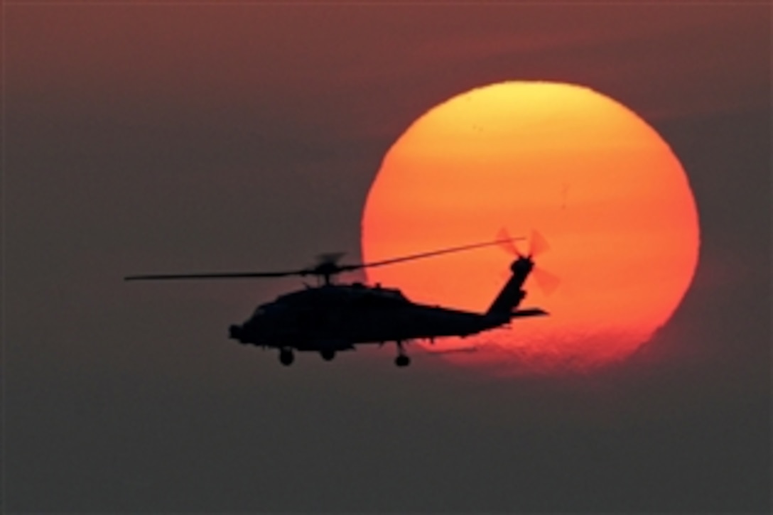 An HH-60H Seahawk helicopter flies over the flight deck of the aircraft carrier USS Dwight D. Eisenhower at sunset in the North Arabian Sea, April 29, 2013. The Eisenhower is deployed to the U.S. 5th Fleet area of responsibility promoting maritime security operations, theater security cooperation efforts and support missions as part of Operation Enduring Freedom. 