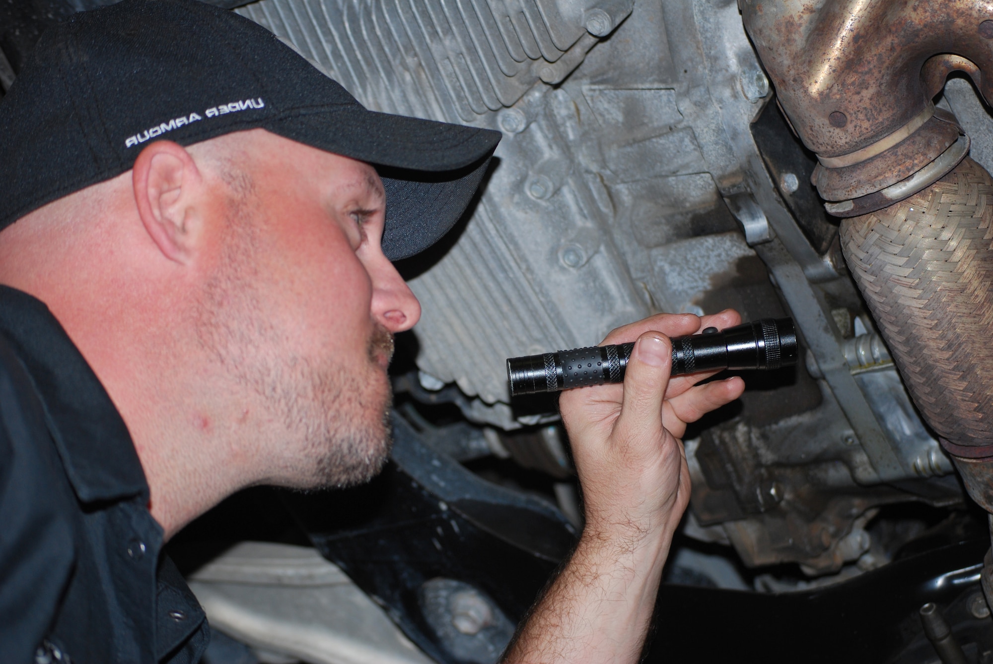 Justin Underwood, 27th Special Operations Force Support Squadron automotive worker, points a flashlight toward the undercarriage of his car to check for an oil leak at the Auto Skills Center at Cannon Air Force Base, N.M., May 1, 2013. The inspection was part of a routine training session to prepare for the Basic Car Care Class at the Auto Skills Center.(U.S. Air Force photo/Desiree Ann Montenegro